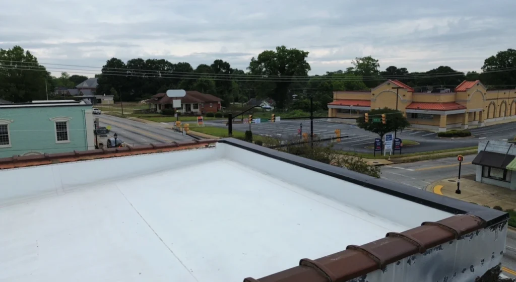 Flat commercial roof installation in Spartanburg SC showing clean white membrane and surrounding businesses